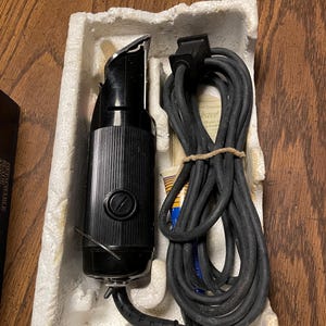 May include: A black electric hair clipper with a cord and a small tube of oil. The clipper is in a white polystyrene box.