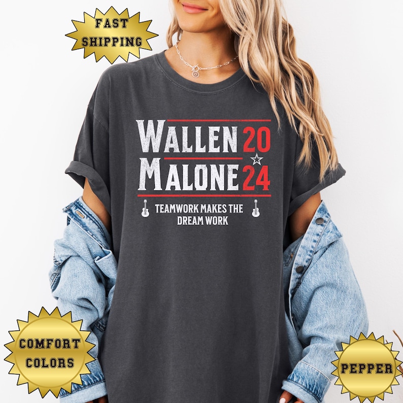 May include: A dark grey t-shirt with the text "Wallen 20 Malone 24" in white with a red star. The text "Teamwork makes the dream work" is below in white with a guitar icon on each side.