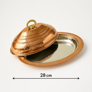May include: A hammered copper serving dish with a domed lid. The dish is 28 cm in diameter and has a silver-plated interior.