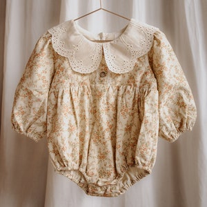 Macacão de veludo cotelê para bebê menina: algodão floral, gola de renda vintage, mangas compridas.