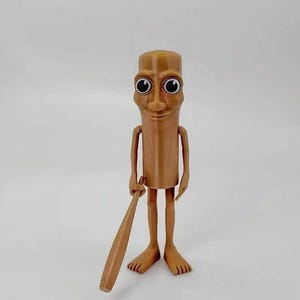May include: A brown figurine of a person with large eyes and a smile, holding a wooden baseball bat. The figurine has a cylindrical body and long, thin legs.