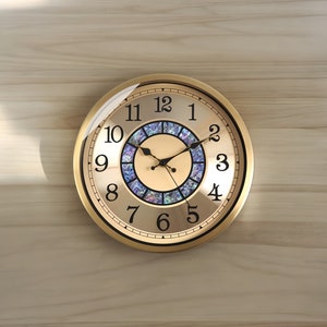 May include: A gold-toned round clock with black Roman numeral hour markers and black hands. The clock face has a decorative, iridescent centre.