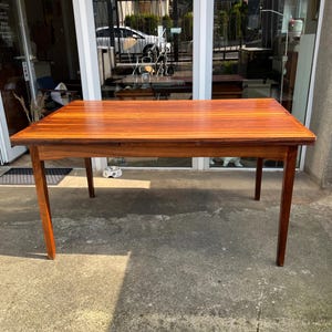 Può includere: Un tavolo rettangolare in legno con finitura marrone-rossiccio. Il tavolo ha un design semplice con quattro gambe dritte e un piano liscio. Il tavolo misura circa 152 cm di lunghezza e 76 cm di larghezza, adatto per mangiare o esporre.