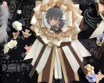 May include: A large, white and brown ribbon rosette with a gold trim. The center of the rosette features a round button with a black and white illustration of a person with black hair and glasses.