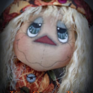 May include: A handmade rag doll with a fall-themed fabric hat and dress. The doll has painted eyes, a stitched mouth, and a button nose. The doll's hair is made of white yarn.