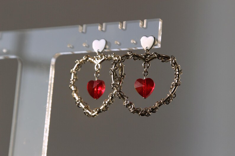 May include: A pair of gold heart-shaped earrings with dangling red heart-shaped crystals.