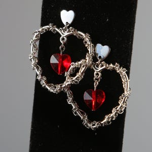 May include: Silver heart-shaped earrings with dangling red crystal hearts.