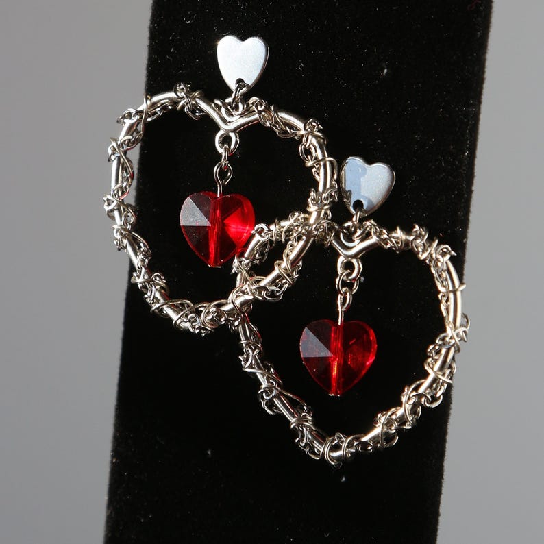 May include: Silver heart-shaped earrings with dangling red crystal hearts.