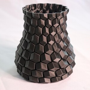 May include: A black, 3D printed vase with a geometric, honeycomb-like pattern.