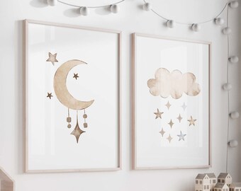 Puede incluir: Dos impresiones de acuarela enmarcadas con un diseño de luna y estrellas y un diseño de nube con estrellas. Las impresiones están colgadas en una pared blanca con una cadena de luces blancas encima.