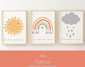 Puede incluir: Tres impresiones enmarcadas con ilustraciones coloridas y texto. La primera impresión presenta un sol amarillo con una cara sonriente y el texto "you are my sunshine". La segunda impresión presenta un arcoíris con un corazón y el texto "you make me happy". La tercera impresión presenta una nube gris con gotas de lluvia y el texto "when skies are grey".