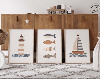 May include: Three framed prints with a nautical theme. The first print features a lighthouse with brown and white stripes, the second print features three fish, and the third print features a sailboat with blue and white stripes.
