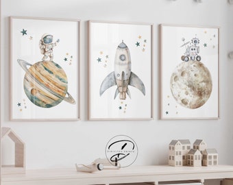 May include: Three watercolor illustrations of space-themed imagery. The first image features an astronaut standing on a planet with rings. The second image features a rocket ship with stars in the background. The third image features a rover on the moon.