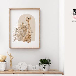 May include: A framed print of a watercolor illustration of a giraffe standing in front of a tan archway with a brown and tan grass-like plant behind it. The print is on a white background and has a wooden frame.