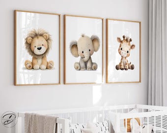 May include: Three framed art prints featuring watercolor illustrations of a lion, elephant, and giraffe. The lion has a tan mane, the elephant has large gray ears, and the giraffe has brown spots. The prints are in wooden frames.