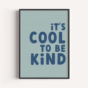 以下が含まれることがあります： 「It's Cool to Be Kind」というメッセージが書かれた、濃い青色の文字の額入りアートプリント。背景は水平線のある水色です。フレームは黒色です。