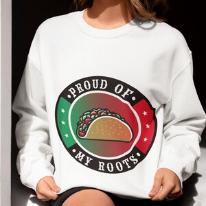 May include: White sweatshirt with a black and red circle graphic. The graphic features a taco with the text "Proud of My Roots".