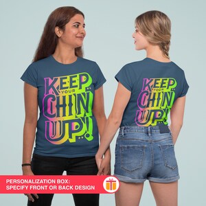 May include: Two navy blue t-shirts with the text "Keep Your Chin Up!" in a rainbow gradient. The text is in a bold, stylized font. The shirts are shown on two models, one facing forward and one facing backward.