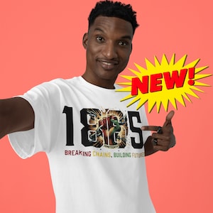 Puede incluir: Una camiseta blanca con un diseño gráfico negro que presenta el año 1865, un puño en alto y las palabras "Juneteenth", "Breaking Chains, Building Futures".