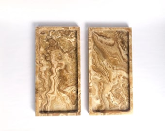May include: Two rectangular trays made of natural onyx with a brown and white marbled pattern.