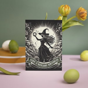May include: A black and white greeting card with a silhouette of a witch holding a glowing orb. The card has the text "Have a Witchin' Birthday" on it.