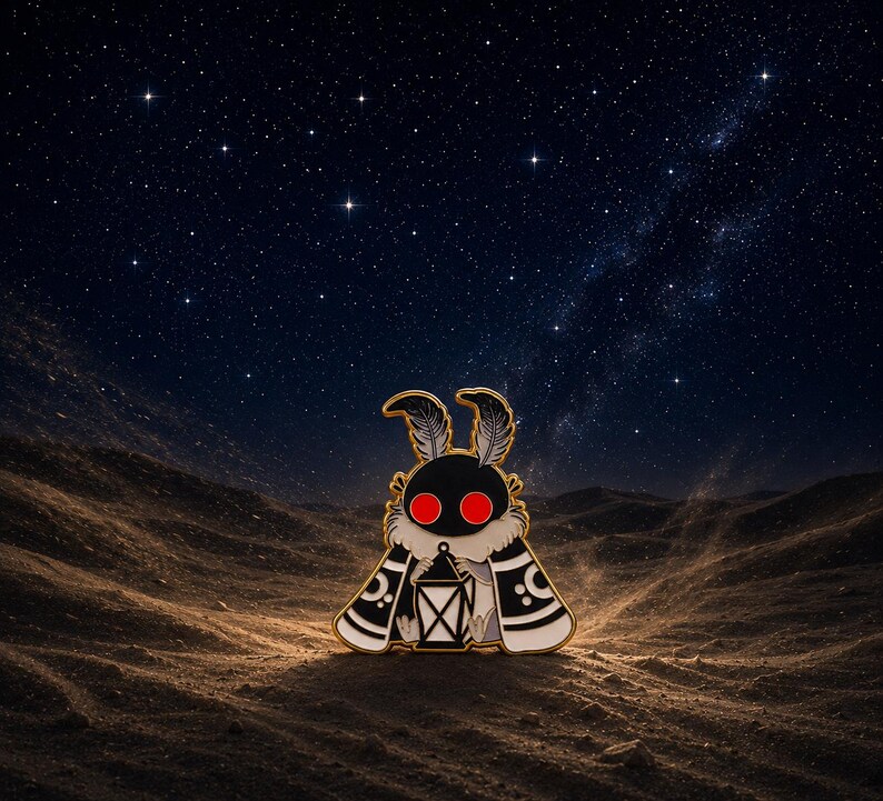 May include: A moth-shaped enamel pin with a black body, red eyes, and a lantern. The pin features gold edging and white details on its wings. The background shows a starry night sky over a desert landscape.