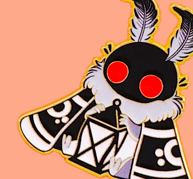 May include: A quirky enamel pin depicting a moth-like character with a black body, red eyes, and white details. The moth holds a lantern and has feathery antennae. The pin has a gold outline and is set against a peach background.