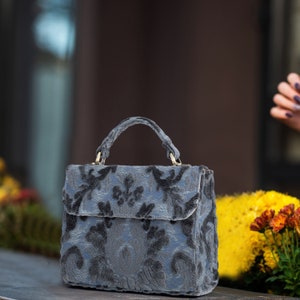 Bolso de mano artesanal con asa superior, bandolera con solapa frontal y terciopelo desgastado azul acero.