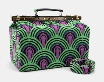 May include: A green and purple doctor's bag with a vintage style design. The bag has a top handle and a removable shoulder strap. The bag is made of a fabric with a repeating pattern of green and purple arches.