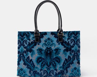 May include: A blue tote bag with a black handle and a floral pattern.
