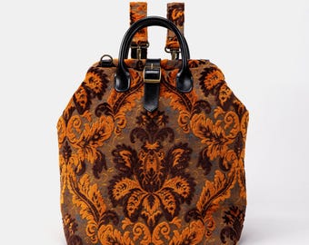 May include: A brown and orange patterned backpack with black leather straps and a buckle closure.