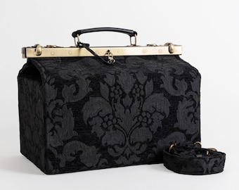 May include: A black doctor's bag with a gold metal frame and a black and white damask pattern. The bag has a black leather handle and a detachable shoulder strap.