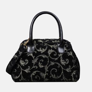 May include: Black handbag featuring a silver floral pattern. It has a top handle and a detachable shoulder strap. The handles and strap attachments are black. The bag's design is a classic style.