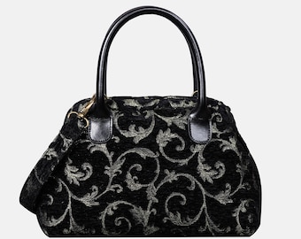 May include: Black handbag with a decorative floral pattern in silver. The bag has a top handle and a detachable shoulder strap. The handles and strap attachments are black. The bag's design is a classic style.