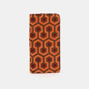 May include: A long, orange and brown wallet with a geometric pattern. The pattern is reminiscent of the carpet in the Overlook Hotel from the movie "The Shining".