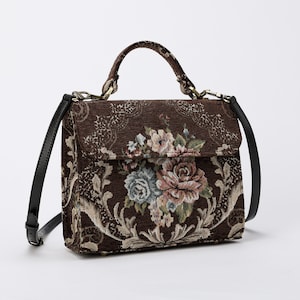 Bolso de mano artesanal con asa superior, bandolera con solapa y diseño floral marrón.