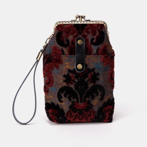 May include: A small, red and black patterned velvet purse with a gold clasp and a black strap. The purse has a floral design.