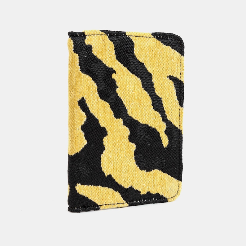 Peut inclure: Un portefeuille en tissu ray&eacute; noir et jaune avec une fermeture &agrave; glissi&egrave;re.