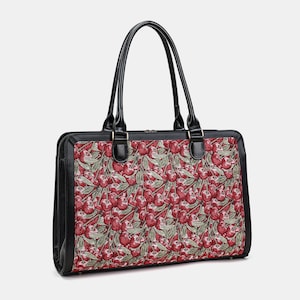 May include: A rectangular handbag featuring a vibrant tapestry pattern of red cherries and green leaves on a dark background. The bag has black leather-like trim, two sturdy black top handles, and a top zipper closure with silver-toned hardware.