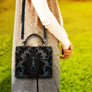 Bolso de mano artesanal con asa superior, bandolera con solapa frontal y acabado en terciopelo negro desgastado.