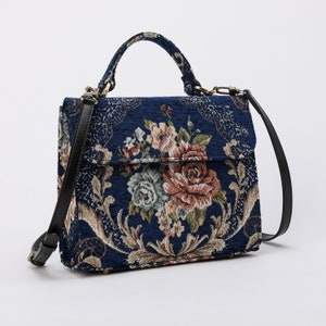 Bolso de mano artesanal con asa superior, bandolera con solapa frontal y diseño floral azul.