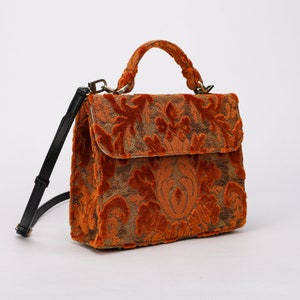 Bolso de mano artesanal con asa superior, bandolera con solapa frontal y terciopelo naranja desgastado.