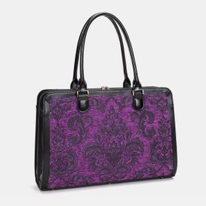 May include: A black and purple tote bag with a damask pattern. The bag has black leather trim, handles, and a zipper closure. The purple fabric features a dark gray floral design.