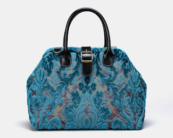 Könnte beinhalten: Eine türkisfarbene Handtasche mit schwarzem Henkel und einer goldenen Schnalle. Die Tasche ist aus einem Stoff mit Blumenmuster.