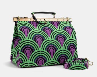 May include: A structured handbag with a repeating arch pattern in green, purple, and black. The bag has a gold-coloured metal frame, a black handle, and a matching detachable shoulder strap. The bag is approximately 30 cm wide.