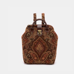 May include: A brown paisley patterned backpack with a brown leather handle and a brass clasp.