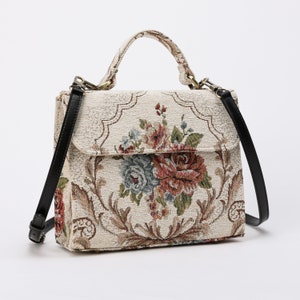 Bolso de mano artesanal con asa superior, bandolera con solapa y estampado floral color crema.