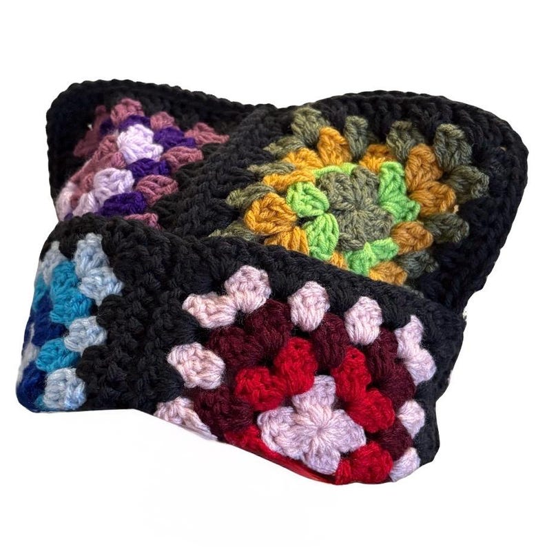 May include: A crochet headband constructed from multiple square motifs joined together. Each square features a black border surrounding a central pattern of yarn in various colors including purple, yellow, green, blue, red, and light pink.