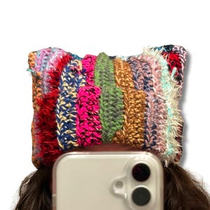 May include: A multi-colored crocheted hat with a variety of textures and colors, including pink, blue, green, brown, and white.
