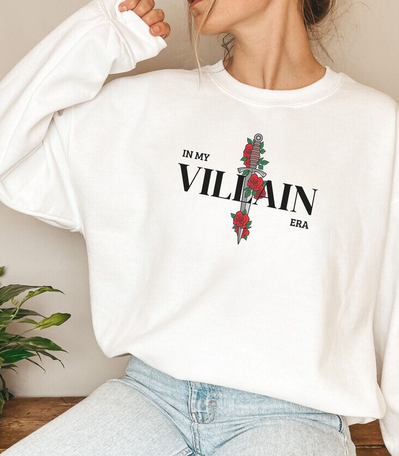 May include: White sweatshirt with a black graphic of a dagger with red roses and the text "IN MY VILLAIN ERA".